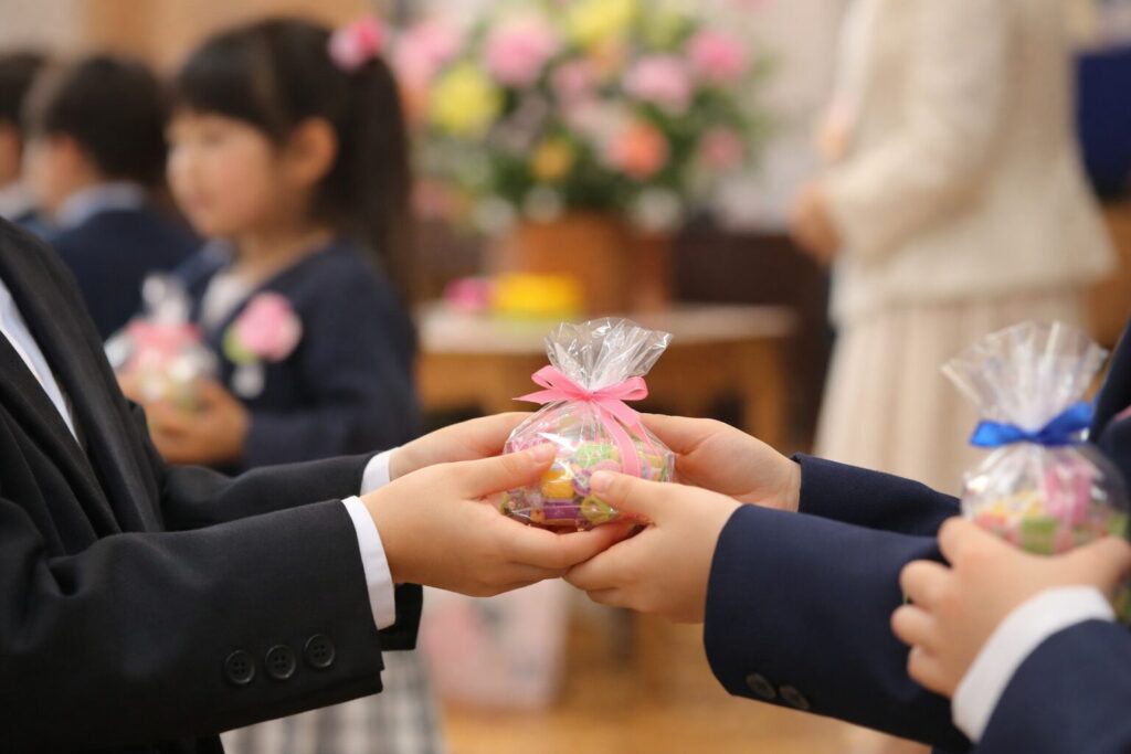 卒園式で友達にプチギフトを渡すか悩む保護者たちの様子をイメージした写真