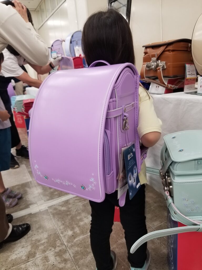 展示会でランドセルを試着する娘の後ろ姿